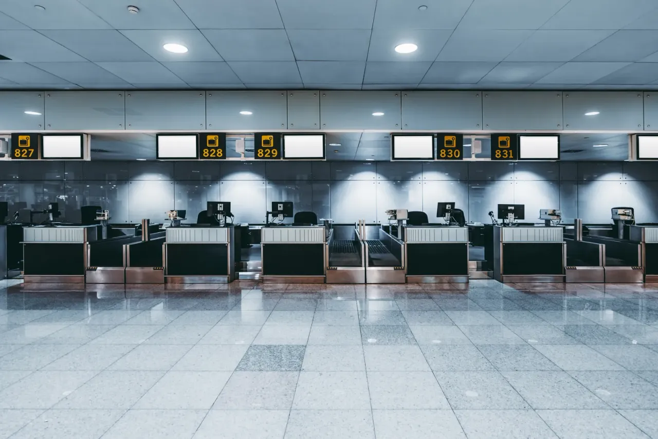 An empty row of airport check-in counters with numbered signs above them and a polished stone floor, typical of the facilities covered by airport and aviation cleaning in Riverside County