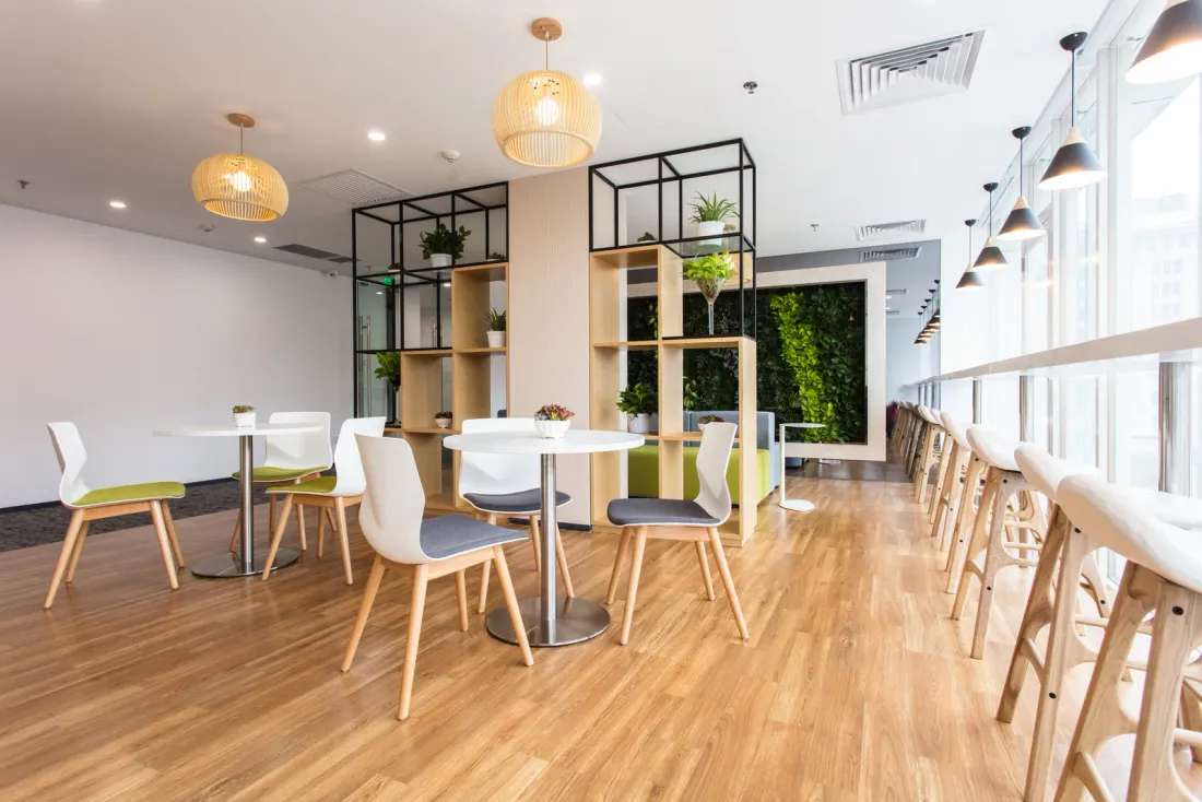 An empty office break area with round tables, white chairs, wooden shelving and a counter along the windows, the kind of space EBS janitorial crews maintain in Vista, CA