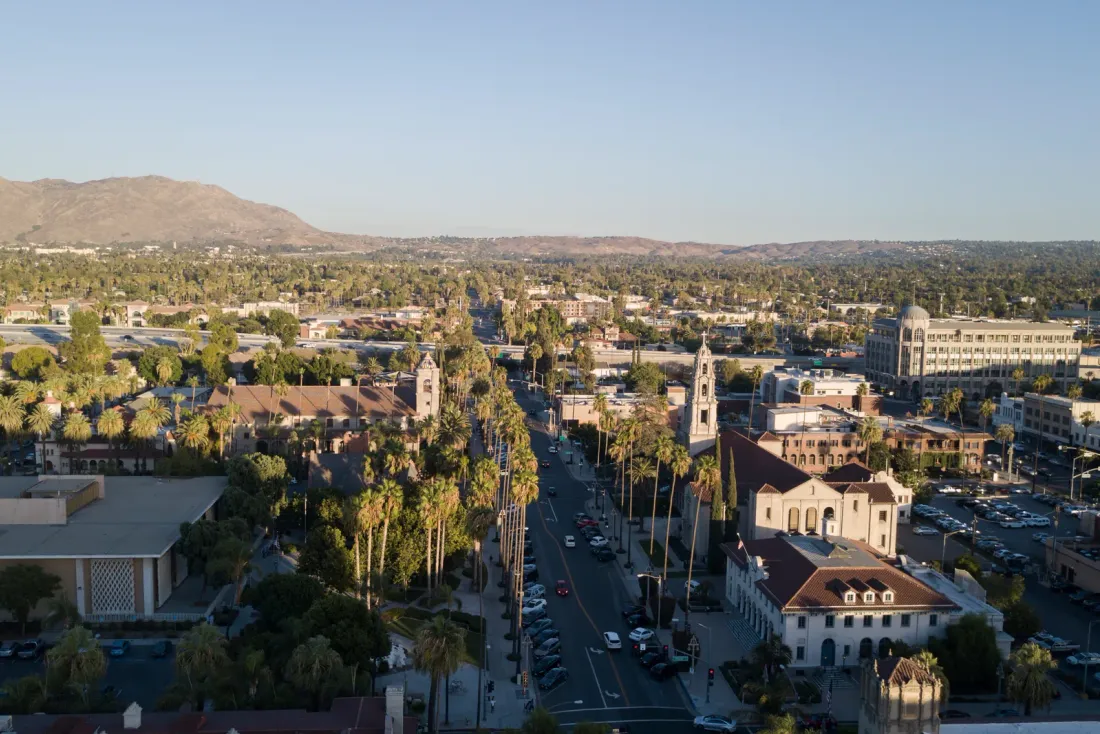 An aerial view of a palm-lined downtown street with low historic buildings and a bell tower, with hills on the horizon, for the EBS guide "Commercial Building Cleaning Services in Southern California"