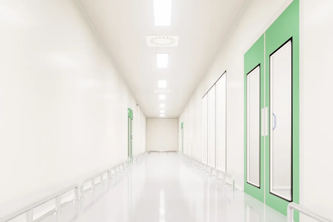 A white cleanroom corridor with a glossy floor, ceiling light panels and green-framed doors, accompanying "How Much Does Cleanroom Cleaning Cost?"