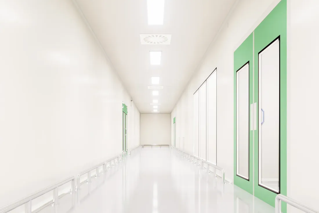 A white cleanroom corridor with a glossy floor, ceiling light panels and green-framed doors, the type of facility covered by warehouse cleaning in Temecula, CA