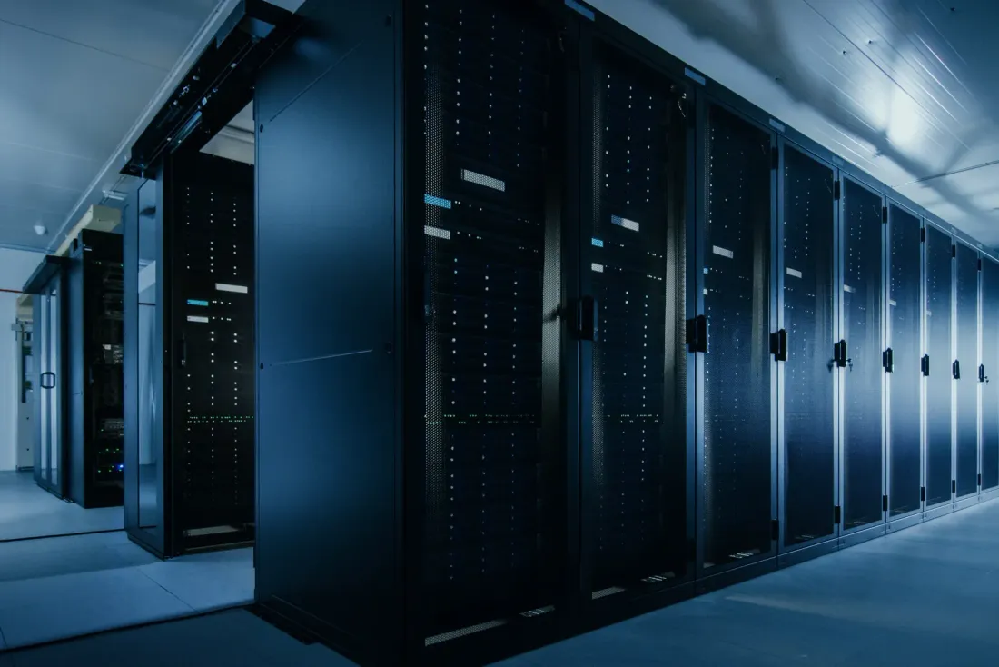 Rows of black server cabinets in a data hall with a raised floor under cool white light, the kind of workspace covered by office cleaning in Irvine, CA