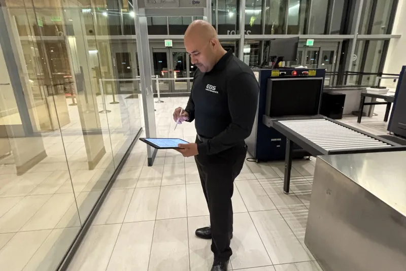 An EBS supervisor reviewing an inspection on a tablet in a lobby after hours