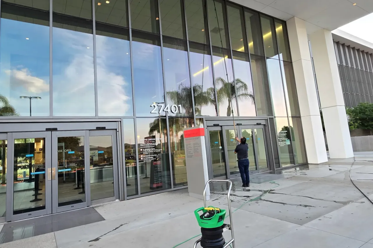 An EBS technician washing the glass facade at a building entrance