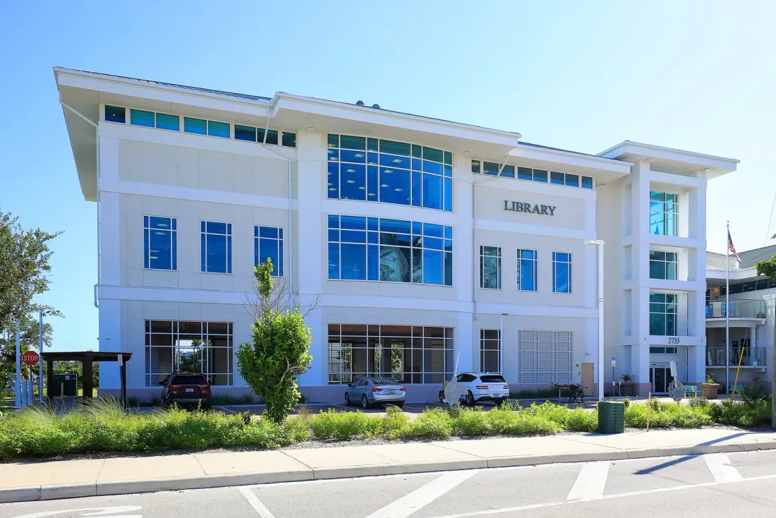A white three-storey building with large windows and LIBRARY lettering, with parked cars and plantings in front, typical of buildings on a recurring janitorial program in Norwalk, CA