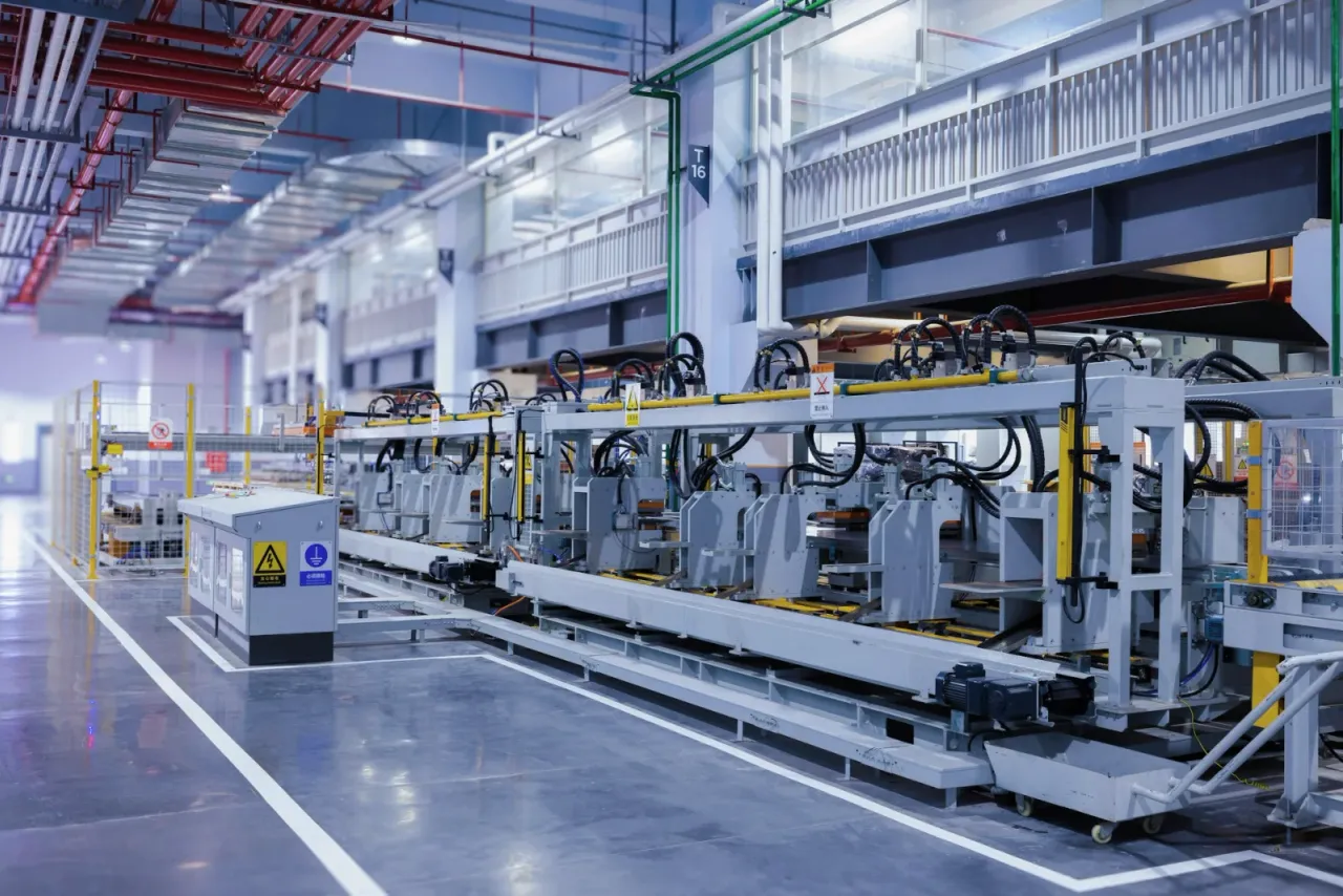 A line of large automated production machines on a polished floor under a steel-framed roof with red sprinkler pipes, the type of commercial property EBS cleans across Carson, CA