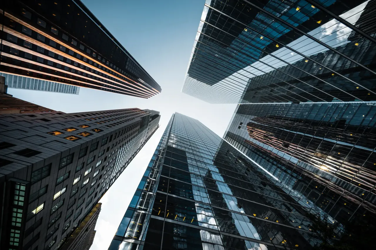 A view straight up at glass high-rise towers from street level, accompanying "What Is Key Control in Janitorial Services?"