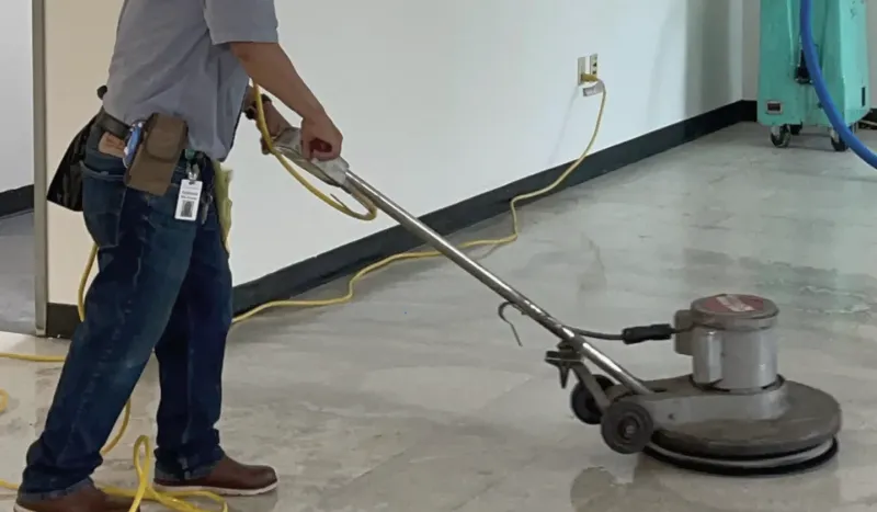 A technician running a floor buffer across a sealed concrete floor