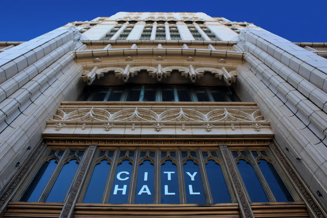 A low-angle view of an ornate stone facade with CITY HALL lettering across its arched windows, a setting for commercial cleaning services in Riverside, CA