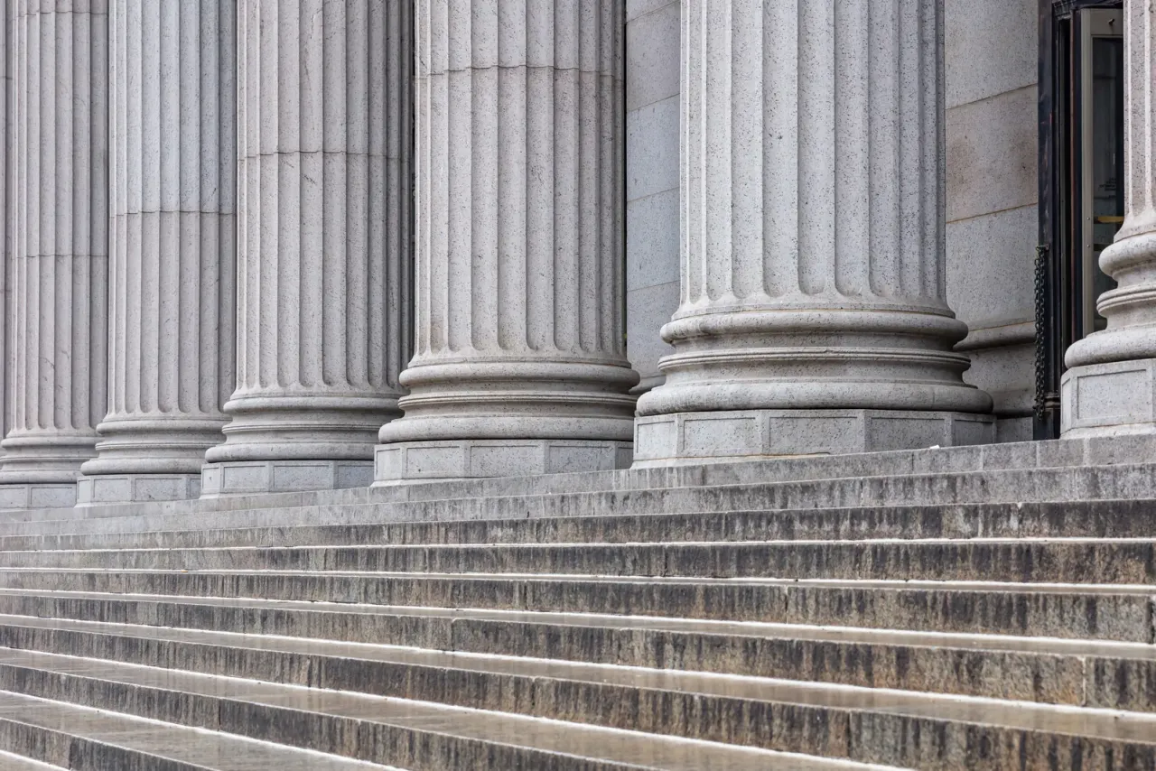 Fluted grey stone columns above wide granite steps at a building entrance, an example of the spaces EBS cleans for this sector in Orange County