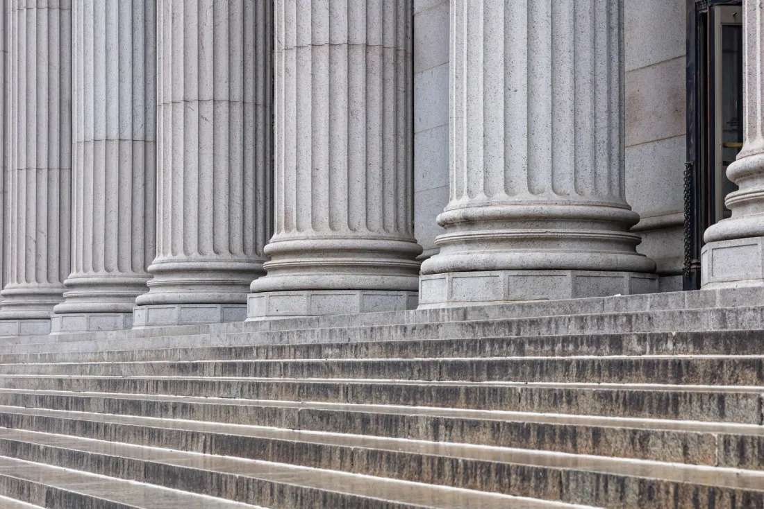 Fluted grey stone columns above wide granite steps at a building entrance, typical of the business properties served by EBS in Indio, CA