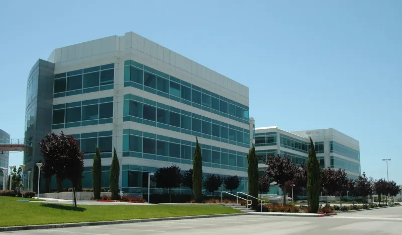 A low-rise office building with tinted glass and palm trees