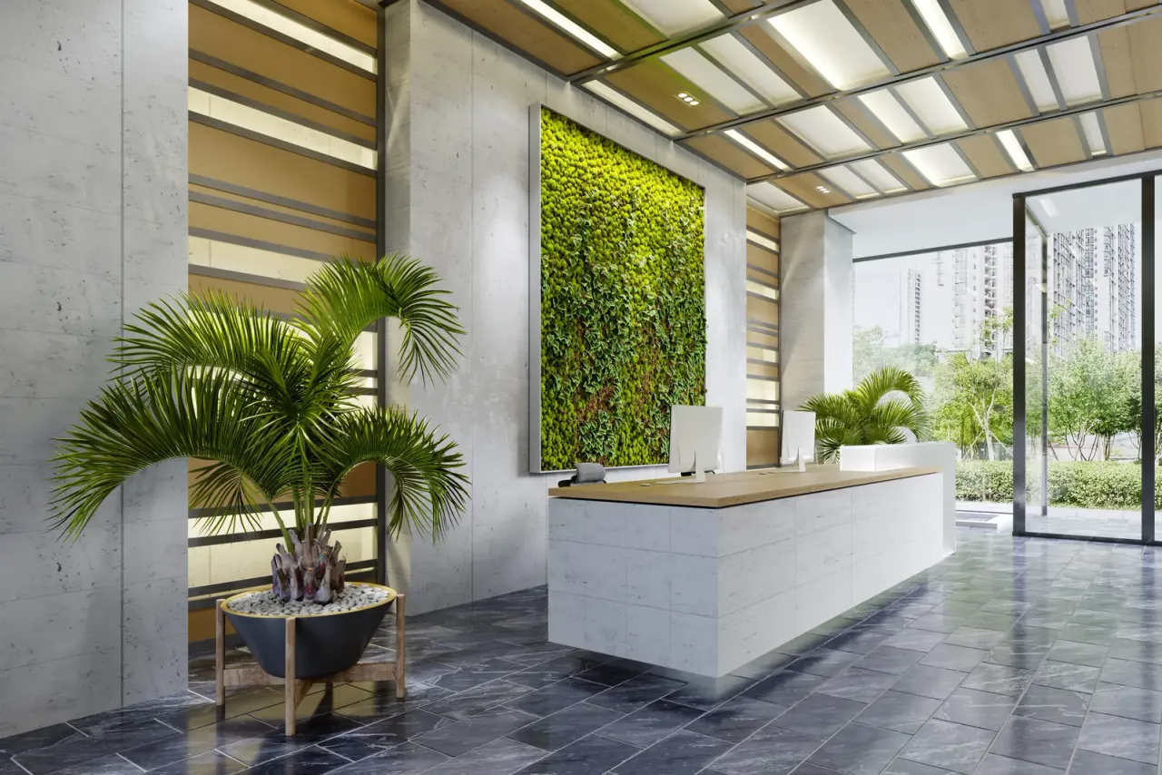A white reception desk in front of a living green wall, with a potted palm, wood-slat ceiling panels and grey stone floor tiles, typical of buildings on a recurring janitorial program in Norwalk, CA