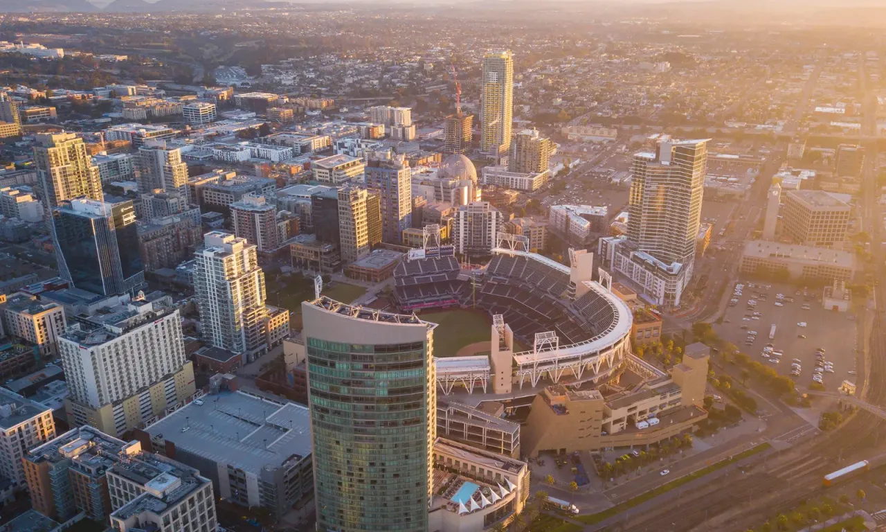 An aerial view at sunset of high-rise buildings surrounding a baseball stadium, illustrating the EBS article "Gym and Fitness Center Cleaning Services"