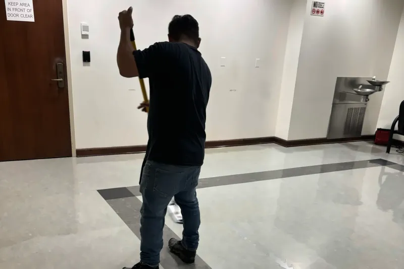 An EBS team member dust-mopping a corridor floor