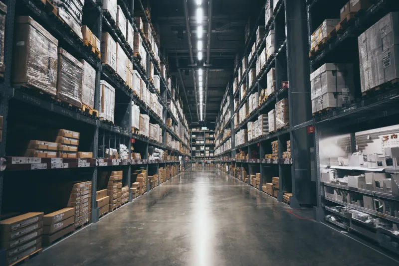 A long warehouse aisle between tall racks of stocked shelving
