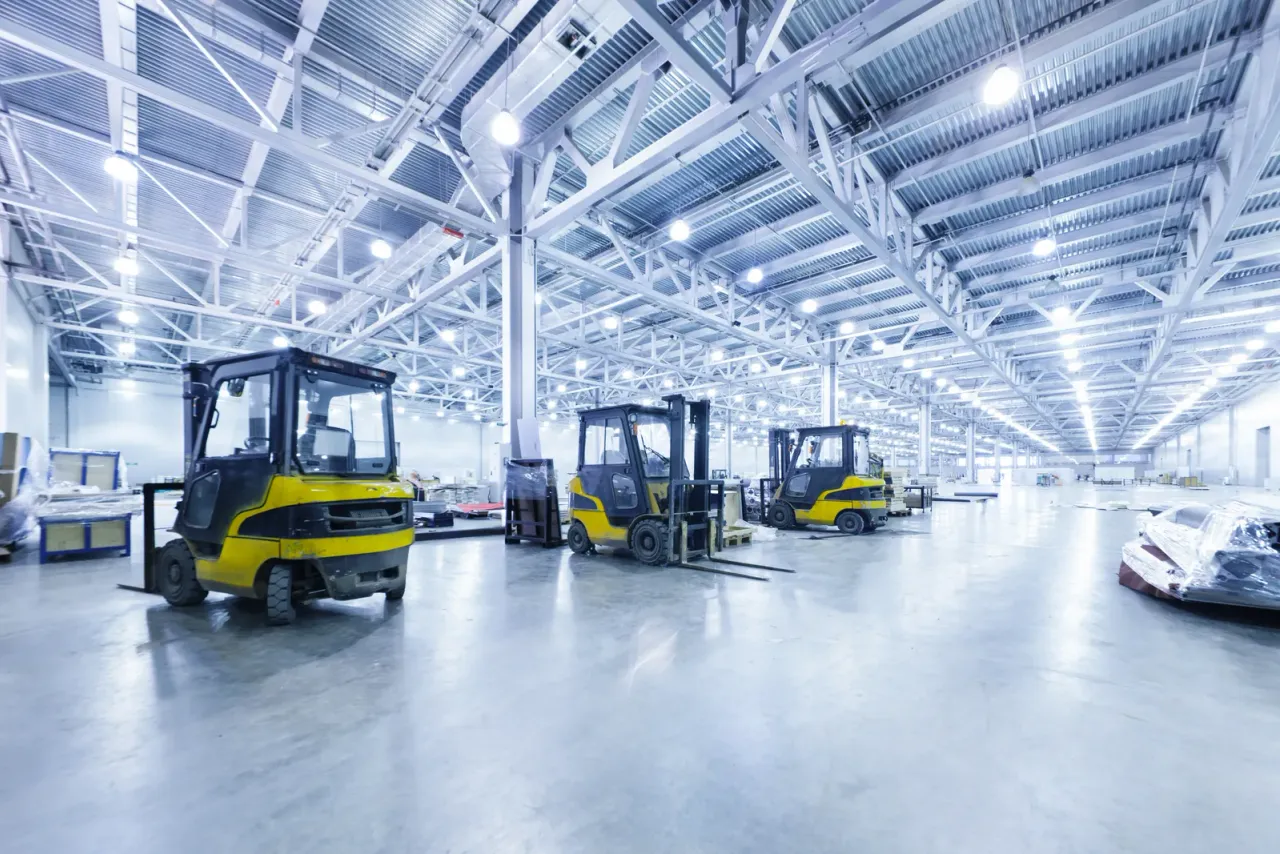 Three yellow forklifts parked on a clean, reflective floor in a bright warehouse with a white steel roof structure, typical of the distribution and industrial space EBS cleans in Temecula, CA