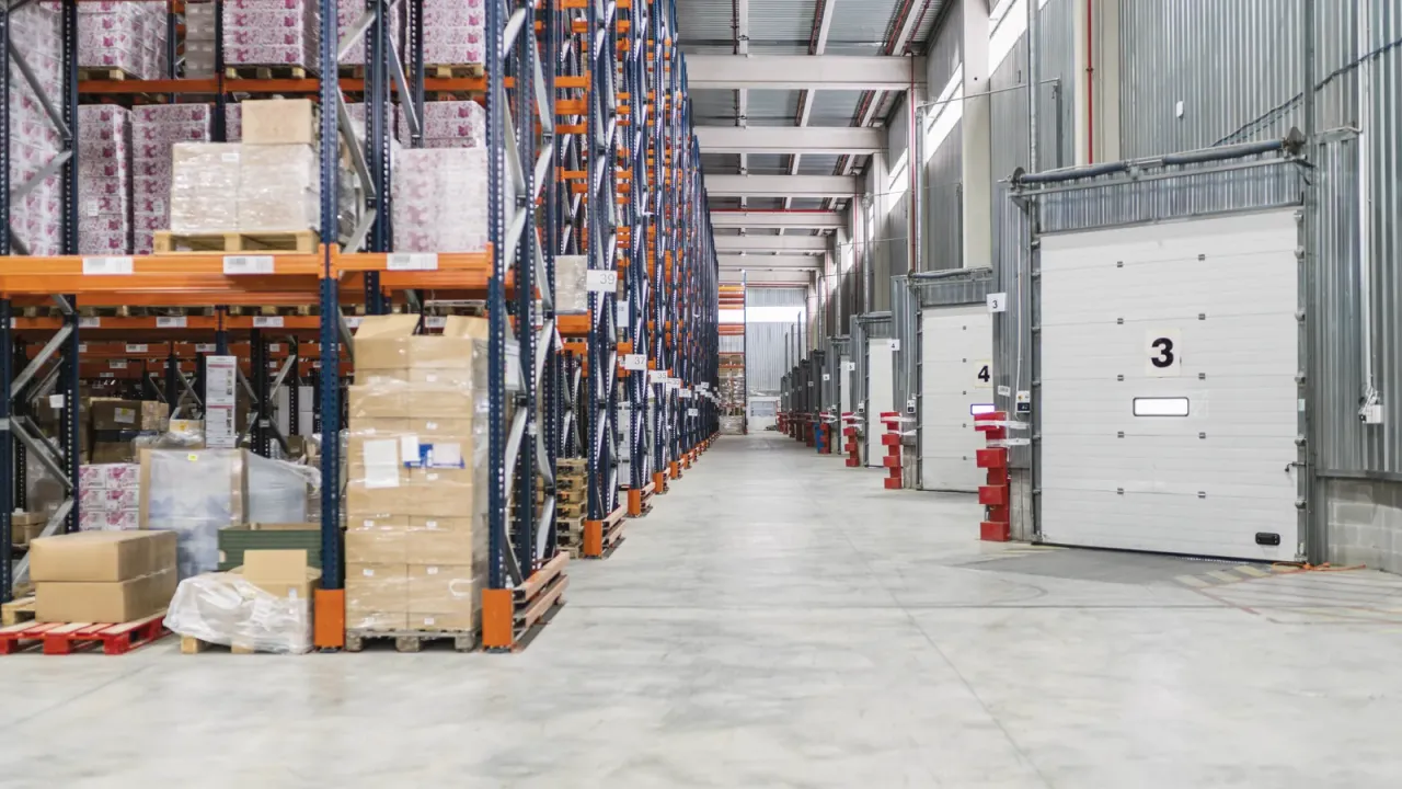 A modern logistics warehouse with pallet racking, loading dock doors and a clean concrete floor